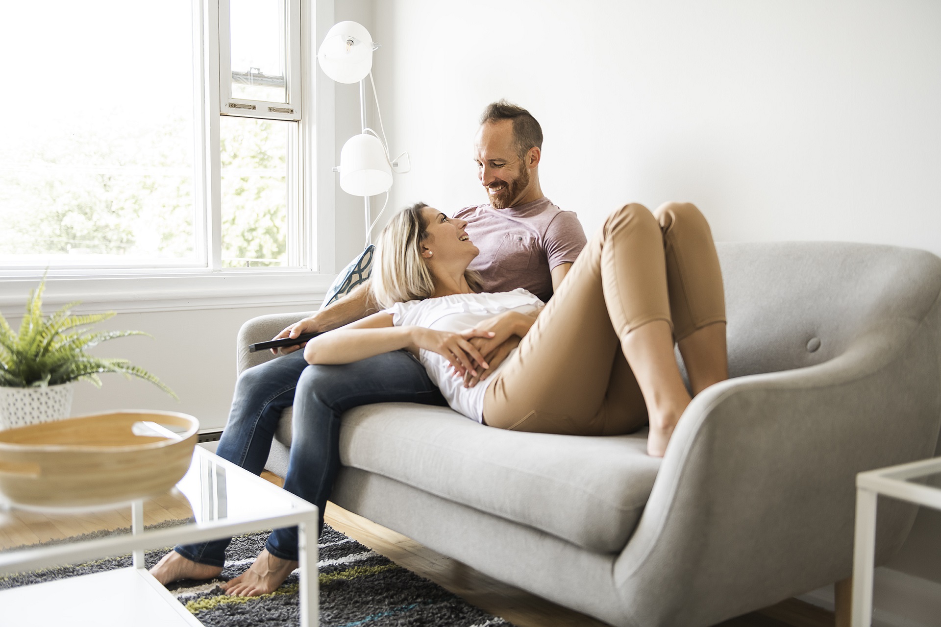 Couple watching tv at home sitting in a comfortable couch in the livingroom at home